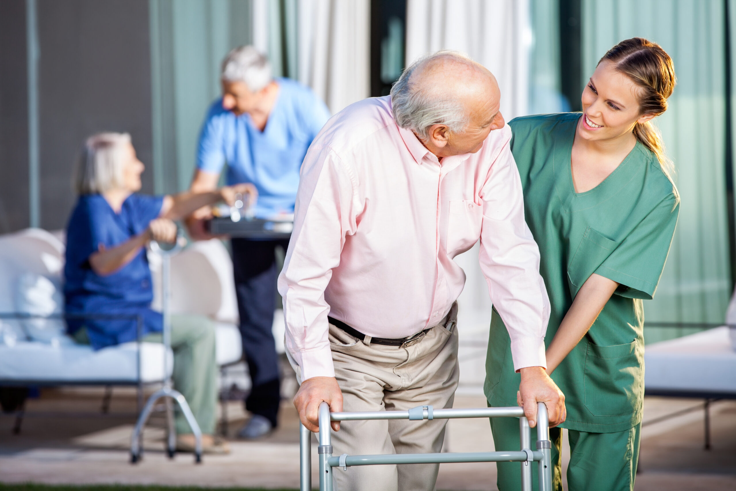 caretaker assists elderly man with walker