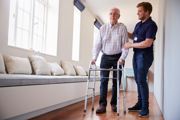 Senior man using a walking frame with male nurse at home|Home Caregiver with senior man in bathroom