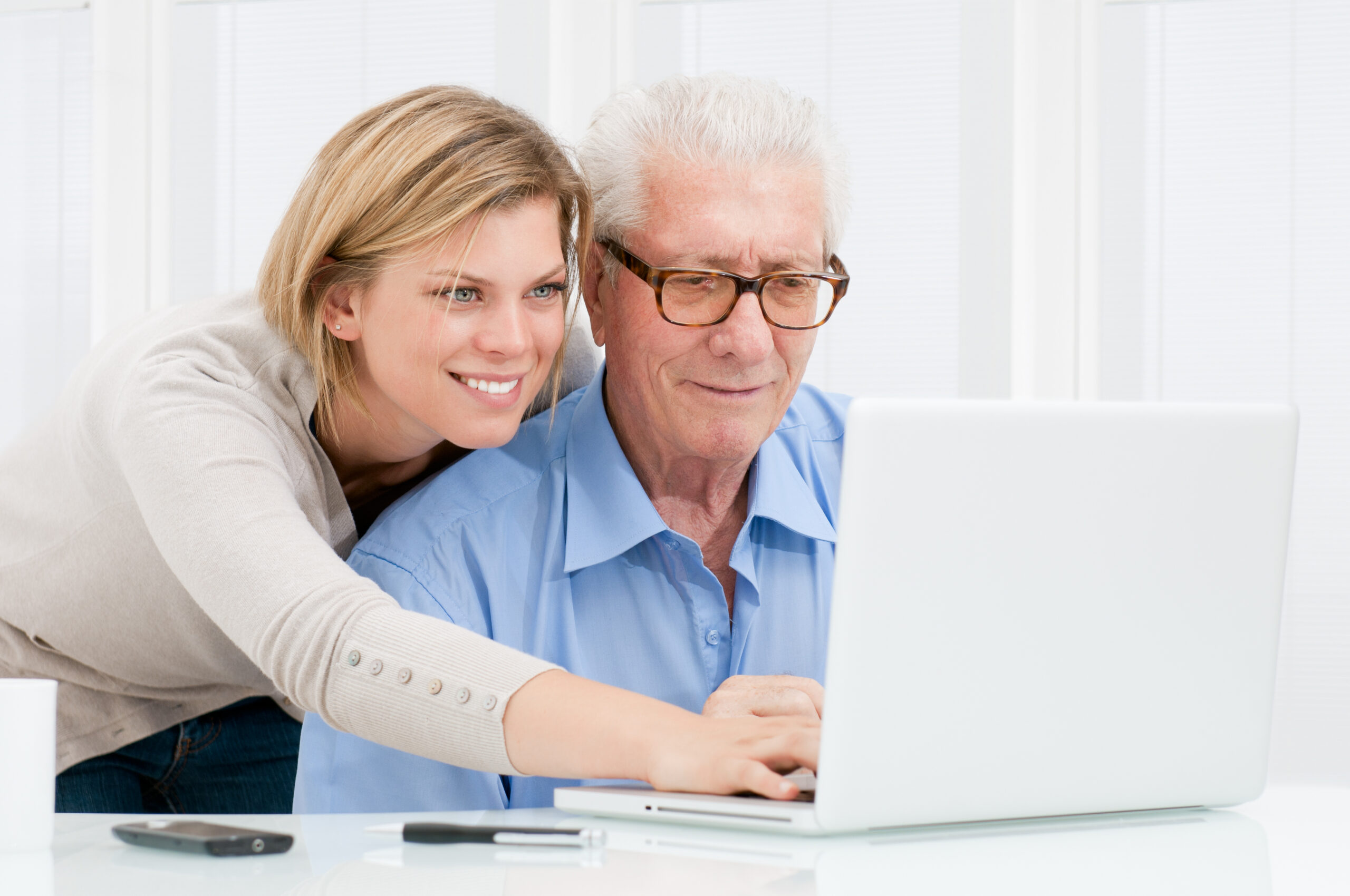 woman helps elderly man with computer