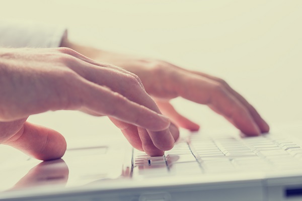 Man typing on a laptop keyboard