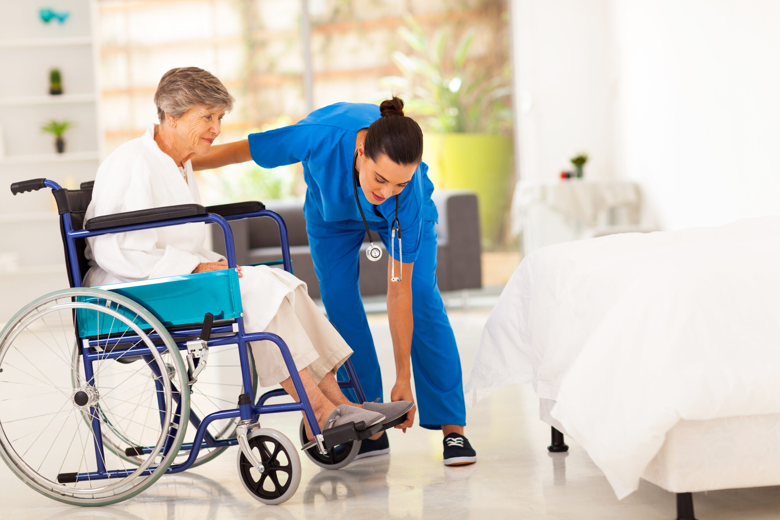 nurse helps elderly woman in wheelchair