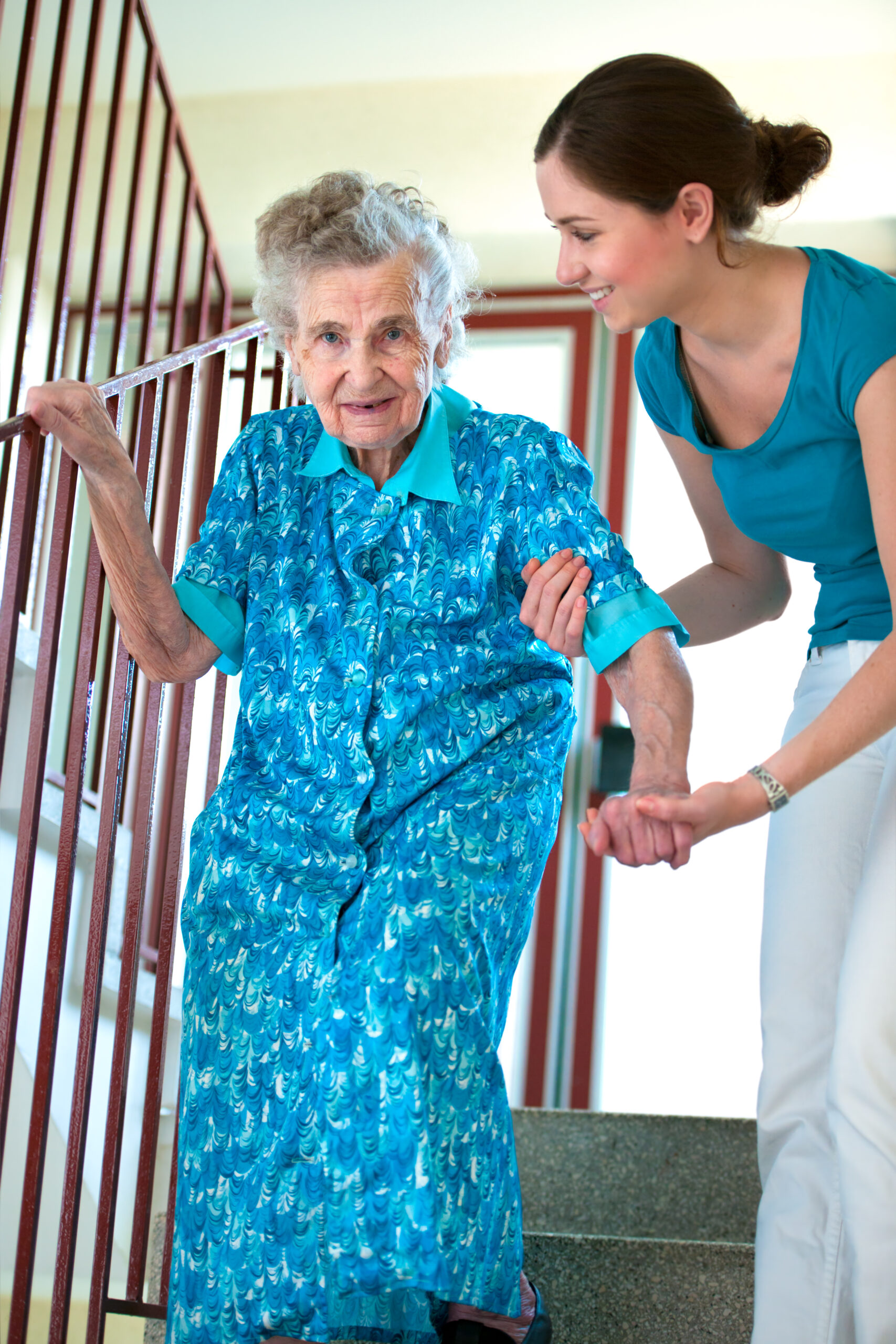 nurse helps elderly woman down stairs